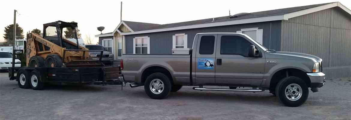 a truck hitched to a trailer with a bobcat on top